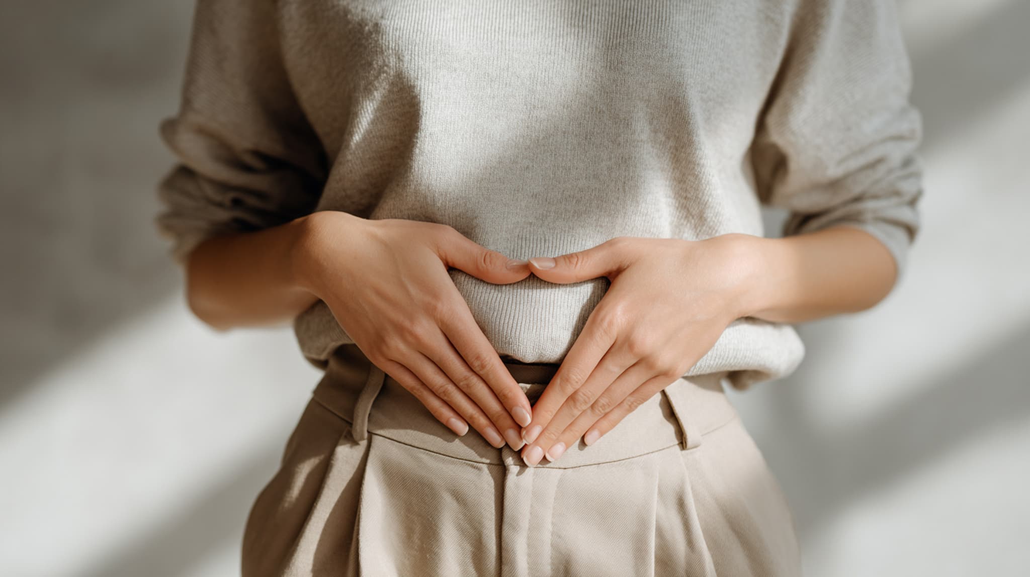 Frau hält die Hände vor den Bauch ein Dreieck formend