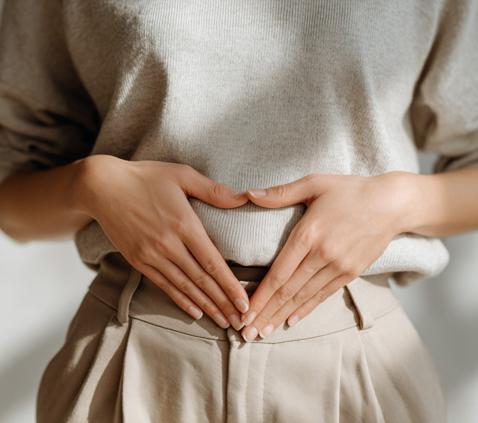 Frau hält die Hände vor den Bauch ein Dreieck formend